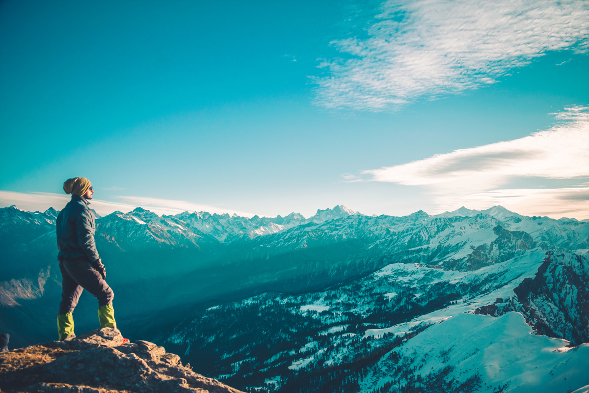 Person Standing on Top of Mountain